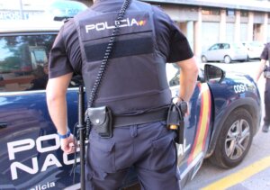 Agente de la Policía Nacional junto a un coche patrulla